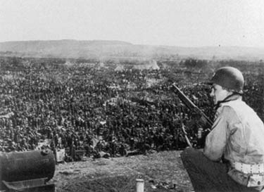 An American soldier guards german prisioners captured in the Ruhr Pocket.